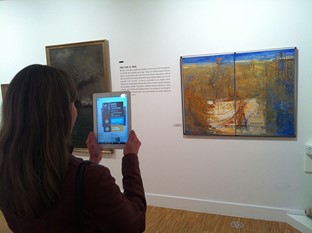 A woman in a musieum using an augemented reality app to retrieve further information on a painting. Creative Commons